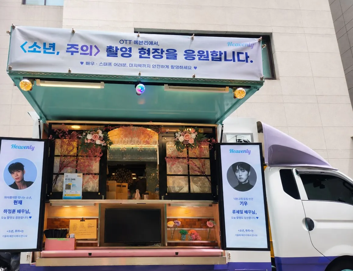 OTT 헤븐리 드라마 소년 주의 촬영장에 세팅된 부르면간다 음료차. 상단 응원 현수막, 하정훈·류세일 배우 배너, 꽃 장식 픽업대